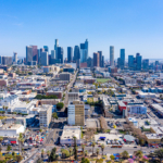 Aerial view of downtown Los Angeles skyline with high rise buildings and surrounding neighborhoods on a clear day.