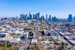 Aerial view of downtown Los Angeles skyline with high rise buildings and surrounding neighborhoods on a clear day.