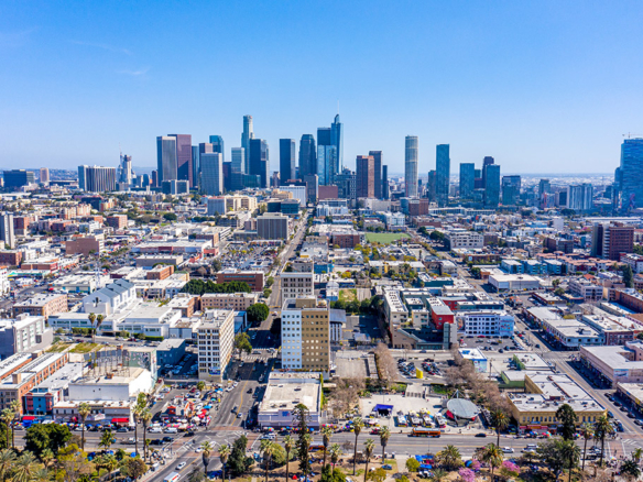 Aerial view of downtown Los Angeles skyline with high rise buildings and surrounding neighborhoods on a clear day.